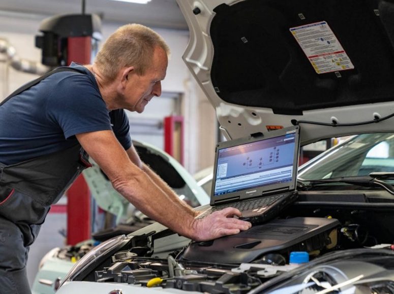 Mechaniker von DEALER BASIS TOP Markenspezialist für [merken] führt eine HU/AU an einem Auto durch.
